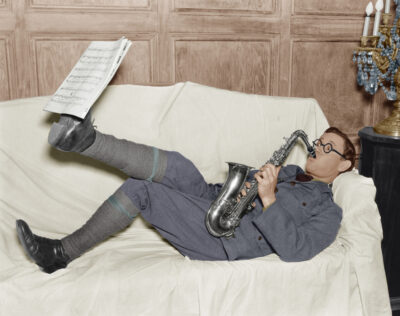 Stock Photo Practice Makes Perfect - Image of man practicing saxophone holding music up with his foot.