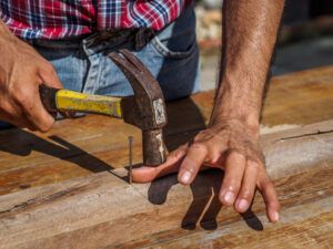 Image of man hitting his thumb instead of nail